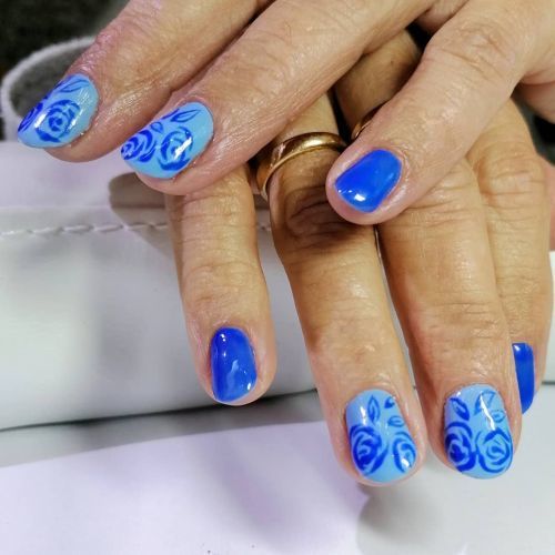 Uñas cortas en azules con garabatos de rosas