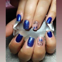 Uñas azules con brillo y atrapasueño de plumas