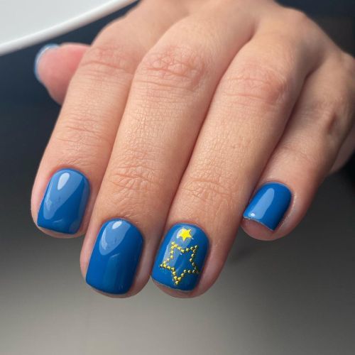 Uñas cortas en azul con estrella de piedrecitas doradas
