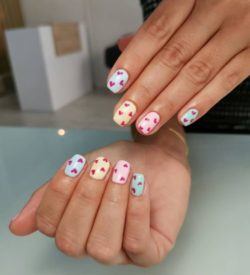 Uñas cortas blancas con corazones de colores