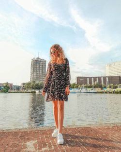 Joven con vestido corto de mangas largas negro con flores y zapatillas blancas